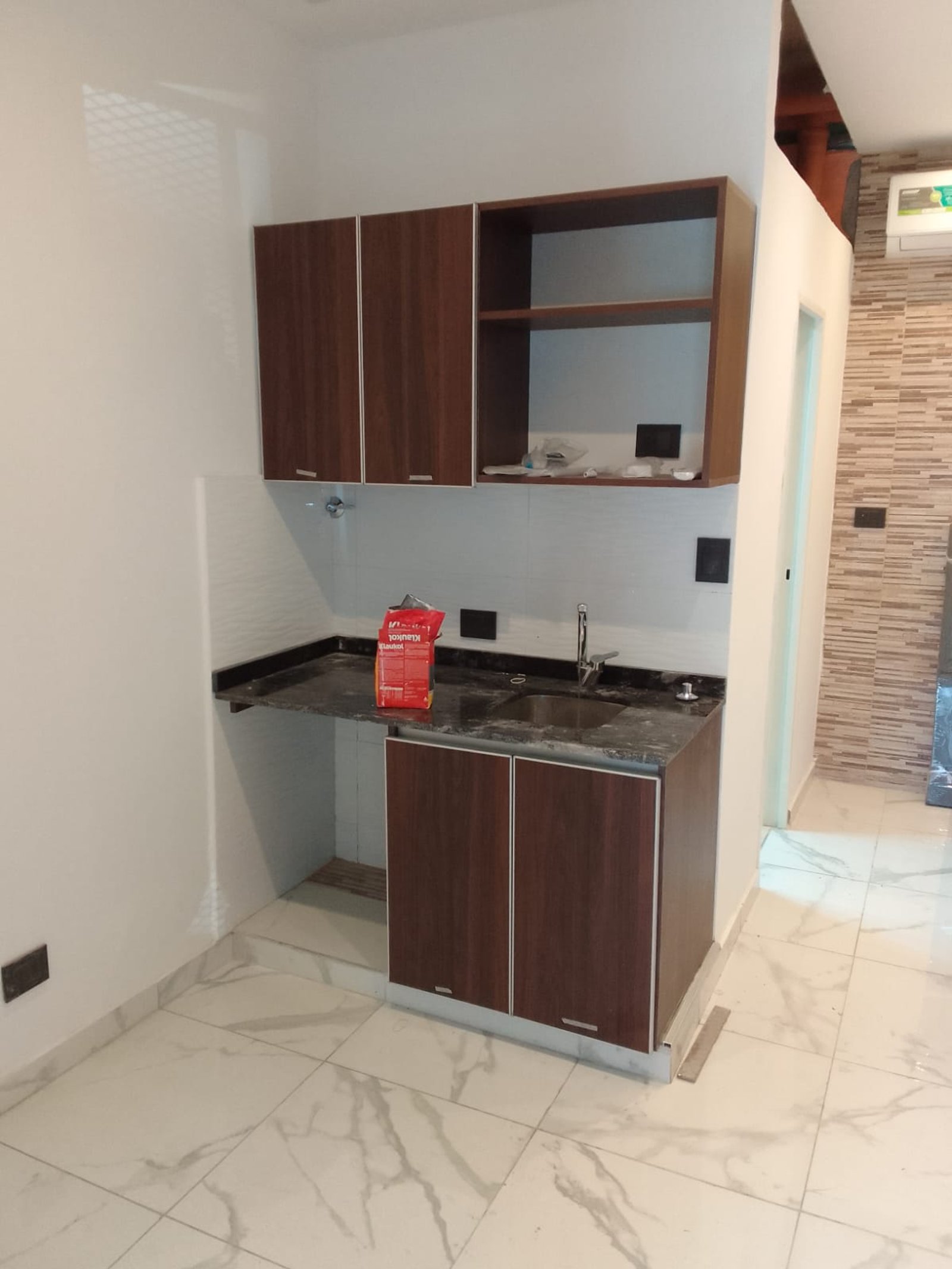 Cocina moderna con muebles de madera oscura y mesada de piedra negra — proyecto Departamentos para turistas en Barracas, por Arquitecto Guido Niccoli, en Barracas